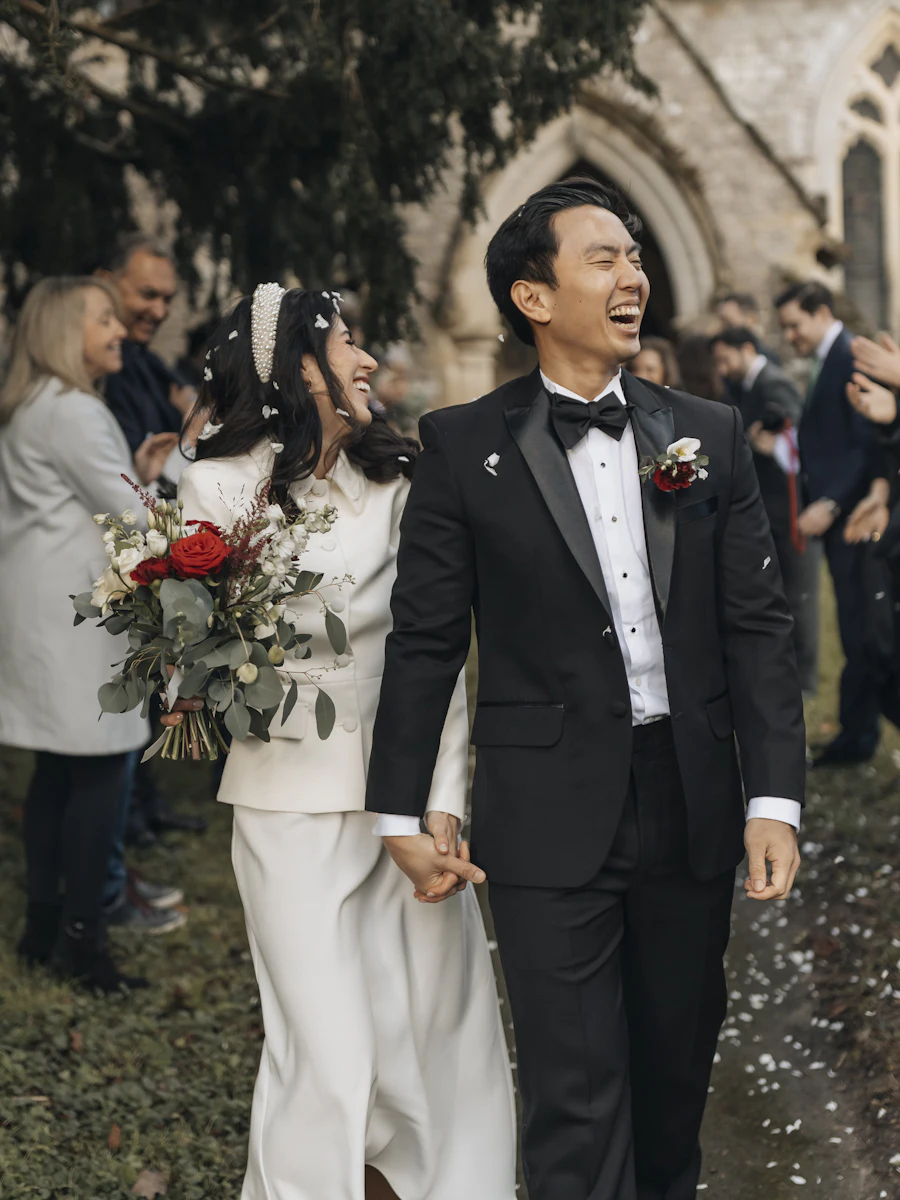A bride and groom laughing as they walk hand in hand after their wedding