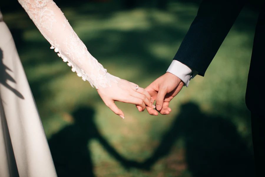 Two hands reaching for each other over green grass
