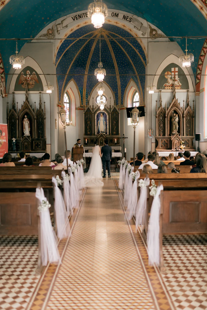 A church decorated with white flowers, with guests seated in the pews