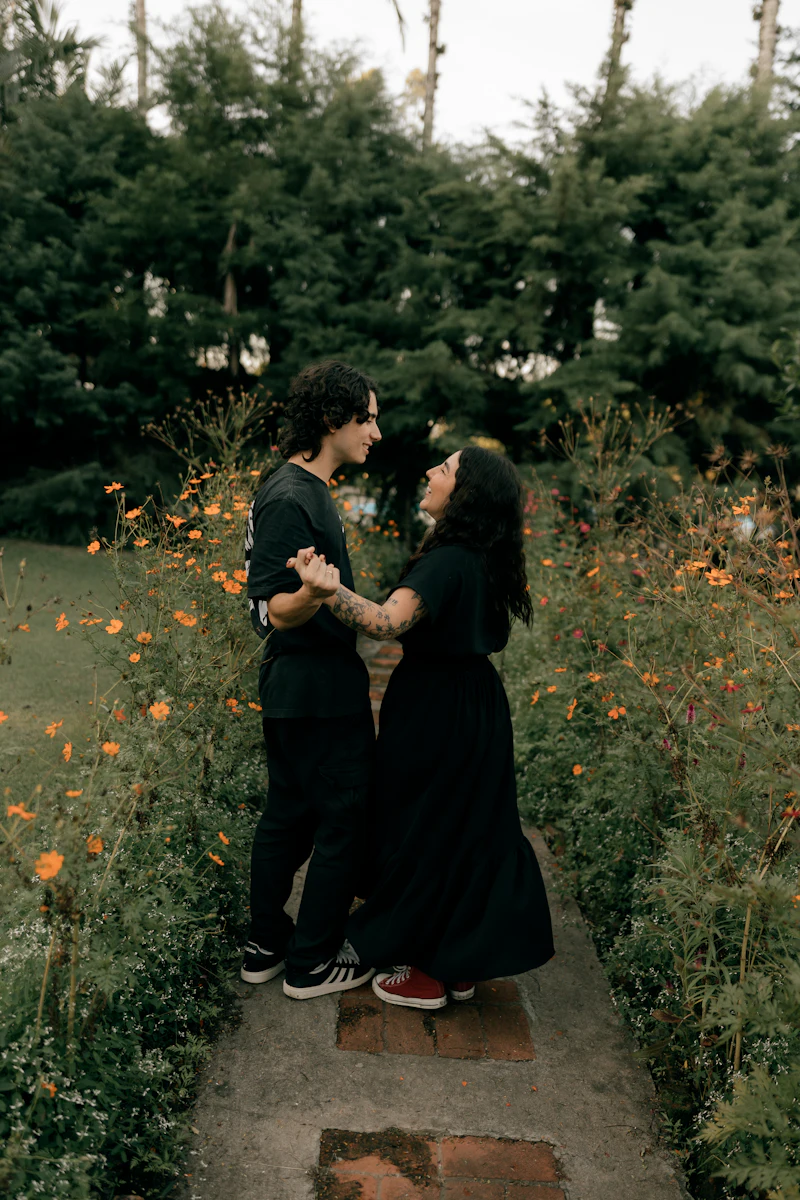 A couple holding hands on a garden path with orange flowers