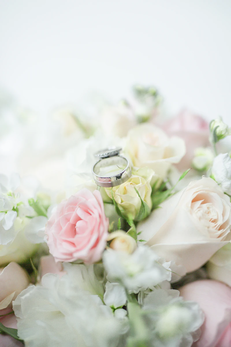 A silver ring resting on a bouquet of white and pink roses