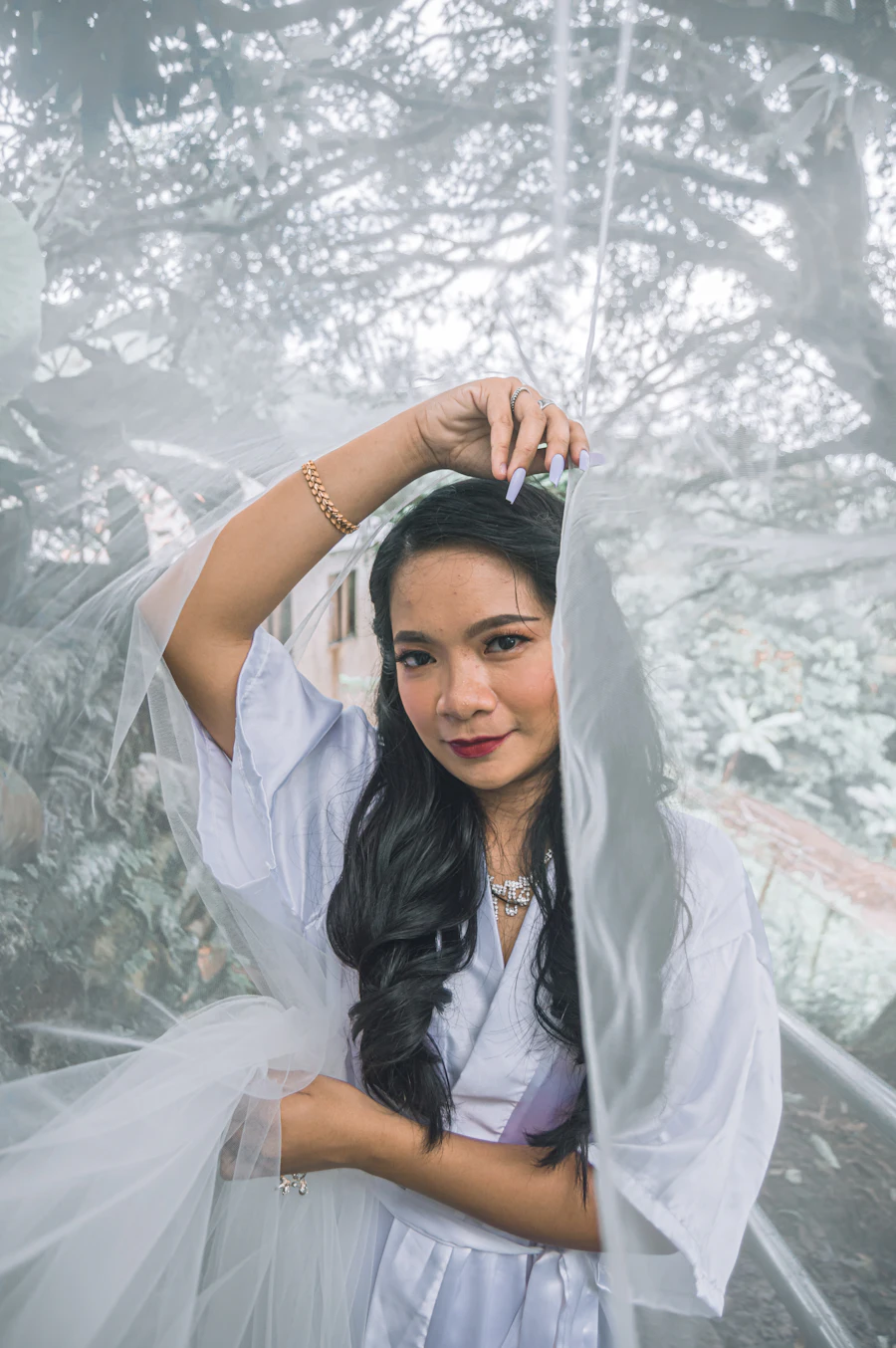 A smiling bride holding her veil over her head