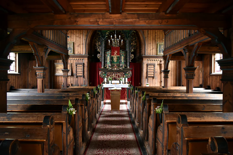 Inside an old wooden church with rows of pews leading to the altar
