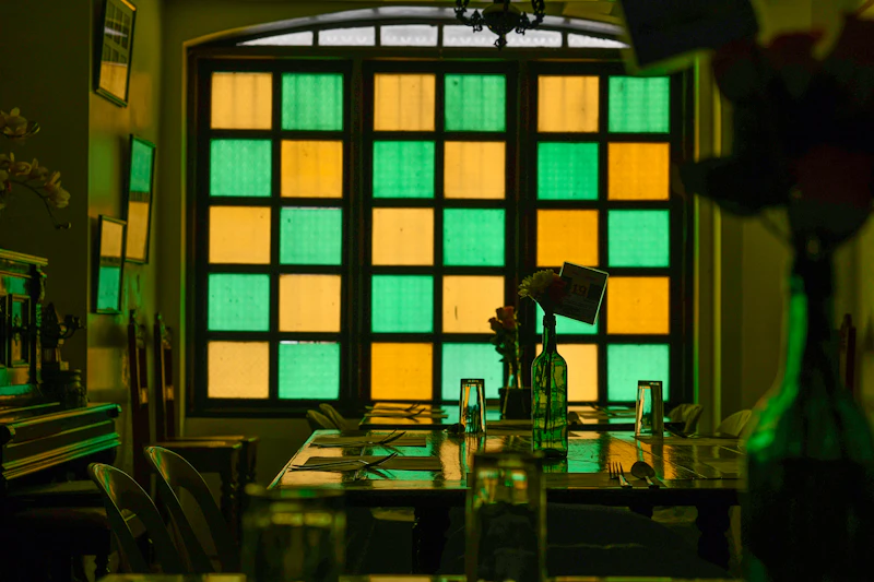 A room in an old house with colored glass windows and a table with flowers