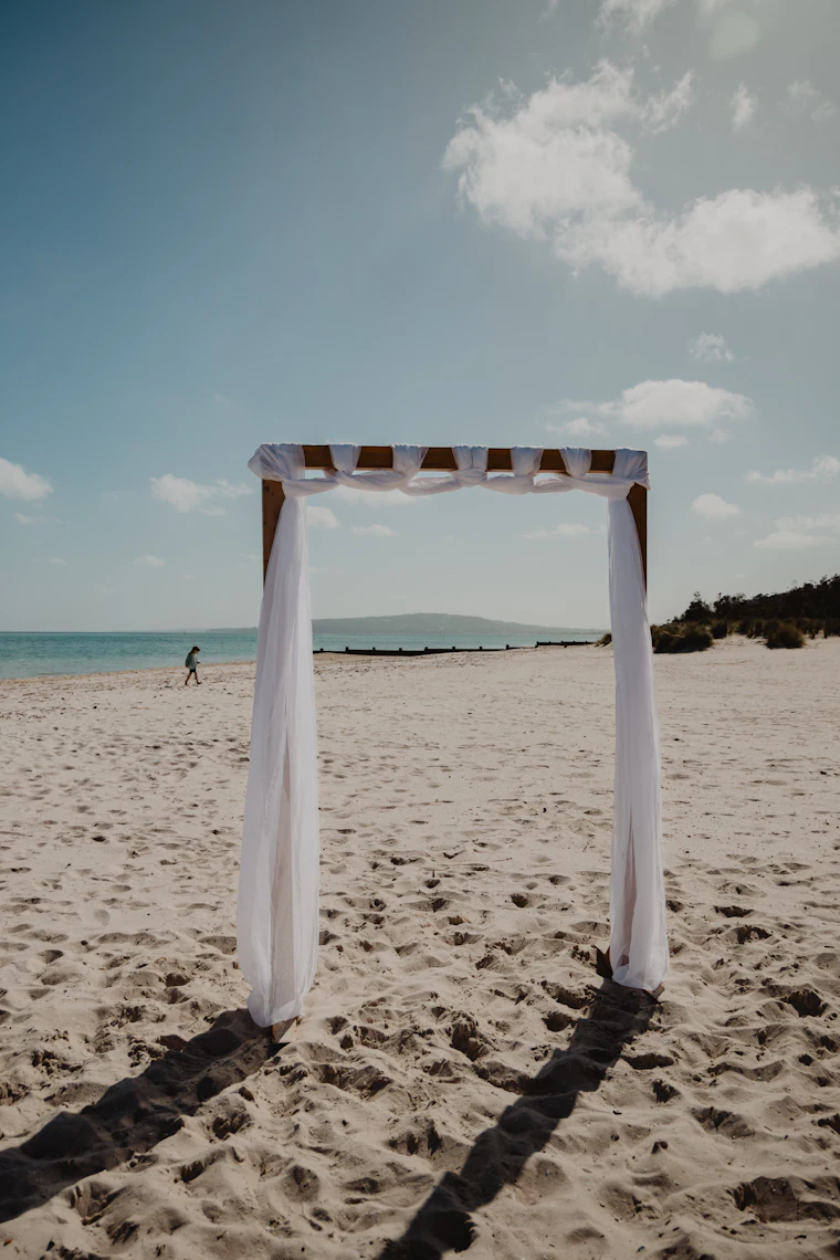 A white wedding arch on a sandy beach