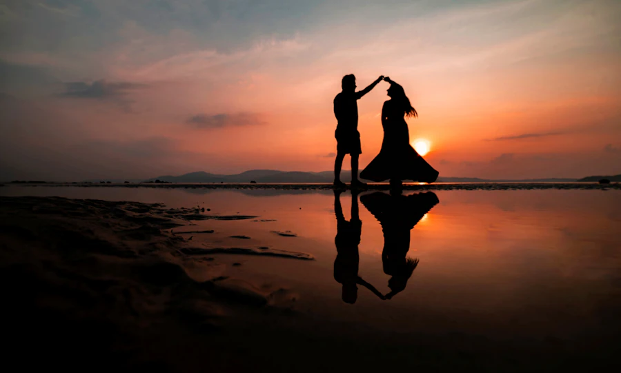 A couple dancing on the beach at sunset, seen as silhouettes