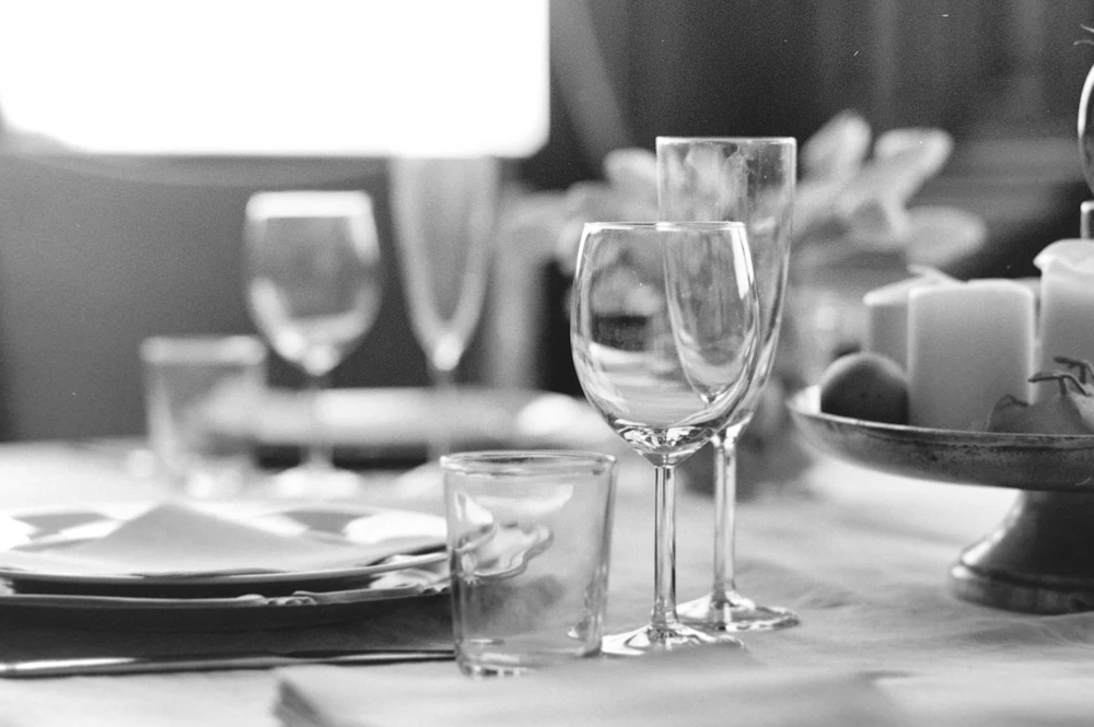 Wine glasses on a set dinner table, in black and white
