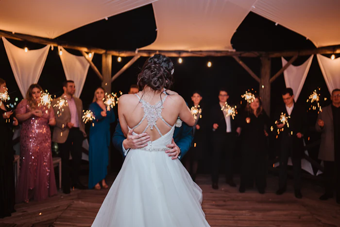 A bride and groom dancing while guests hold sparklers