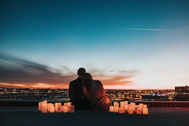 Two people sitting behind glowing candles, looking out over the city
