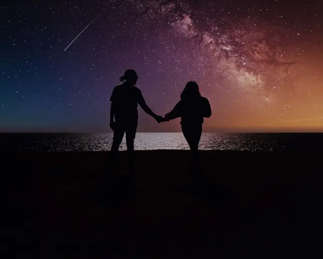 Two people holding hands under the Milky Way